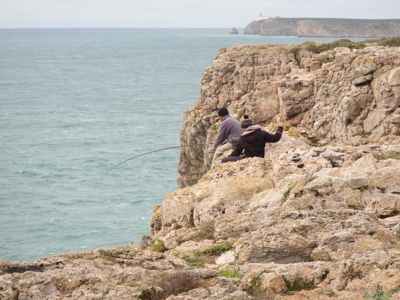 Fishermen straddling the cliffside bringing in their meal